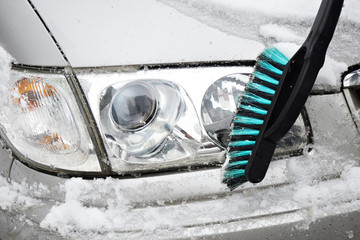 Man cleans car from snow with brush