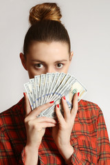 Young woman covering her face with bunch of dollar bills