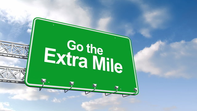 Go the extra mile sign against blue sky