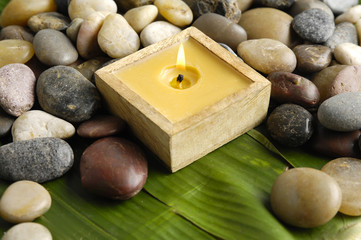 Fototapeta na wymiar Handmade candle and pebbles on banana leaf
