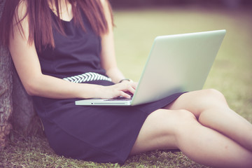 Naklejka premium Beautiful young woman using laptop in park