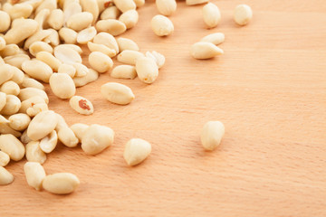 Fototapeta na wymiar Peeled peanuts on wood background