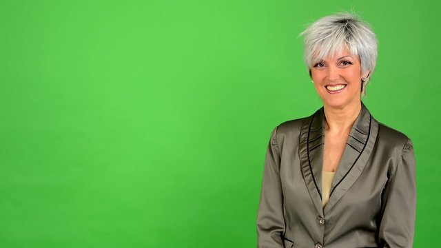 business middle aged woman smiles - green screen - studio