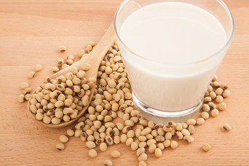 Soy milk in glass with soybeans and wooden spoon