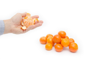 Peeled orange held by a hand with a pile of oranges