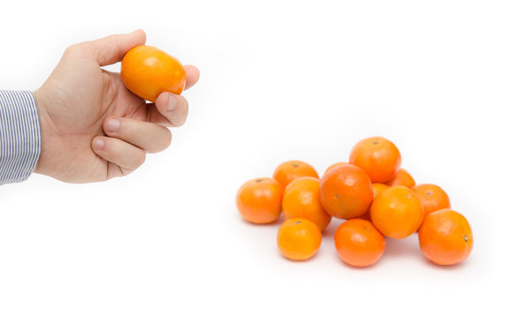 Hand holding a ripe orange with a pile