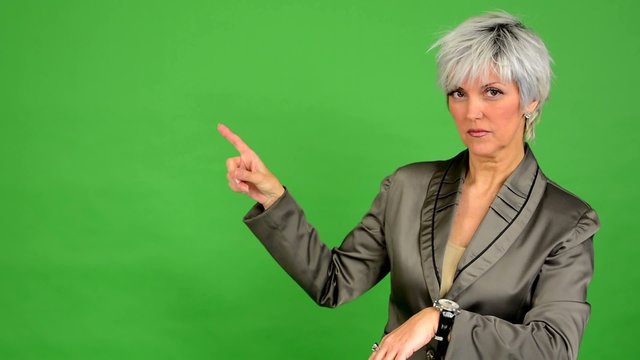 business woman points to watch - green screen