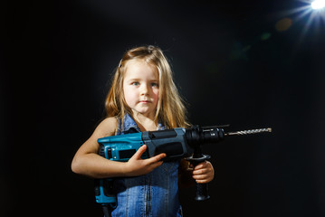 Cute little girl with drilling machine in her hands