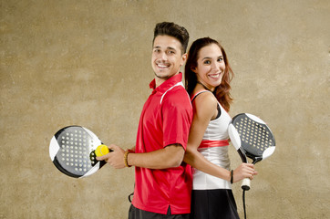 Paddle tennis couple posing on concrete wall court