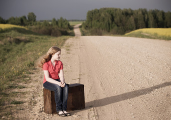 sad girl on road with vintage suitcases