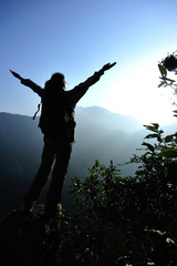 cheering woman hiker open arms at mountain peak 