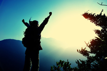 cheering woman hiker open arms at mountain peak 