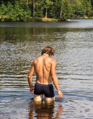Athletic man goes in lake water