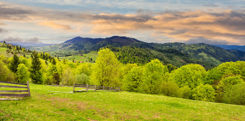fence on hillside meadow in mountain at sunrise
