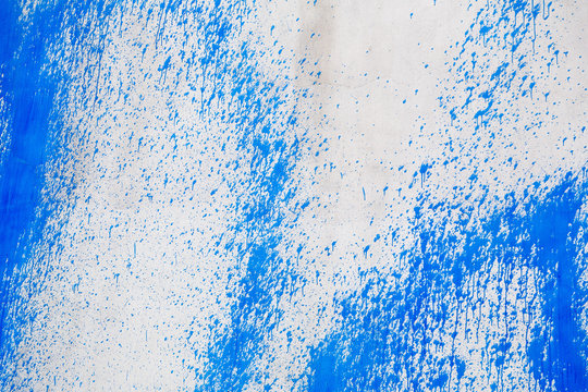 Concrete wall with blue paint splatters