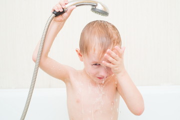 cute 4 year-old boy bathes in a shower