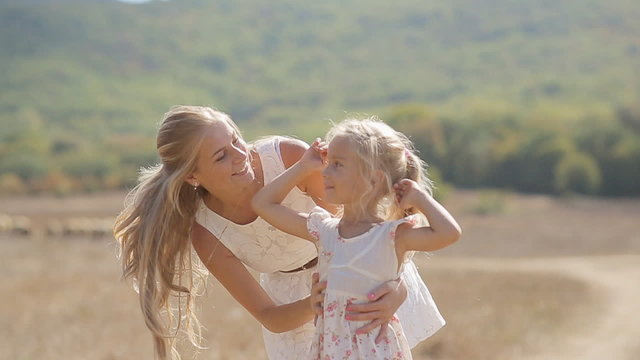 Young beautiful mother kissing little daughter and circling her