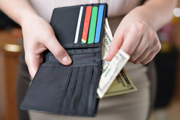 Black purse with money in woman`s hand