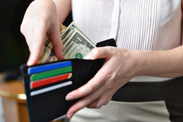 Black purse with money in woman`s hand