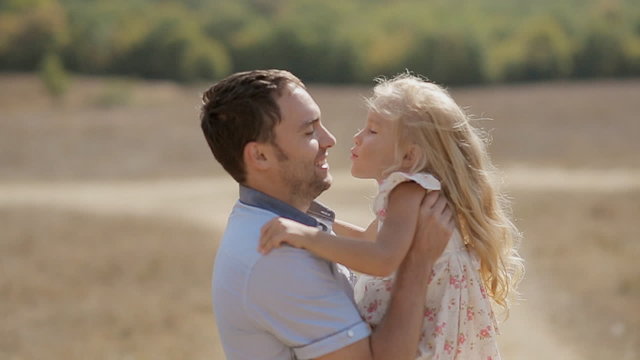 Dad raises his little daughter in arms and they hug and kiss