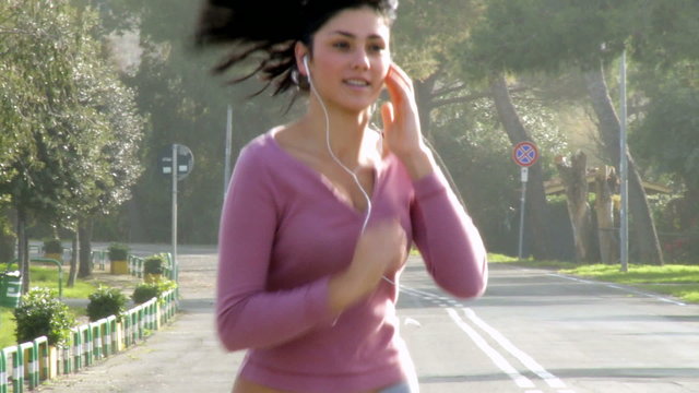 Gorgeous woman jogging on street listening music