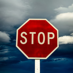 Obraz premium roadside red stop sign on a cloudy background.