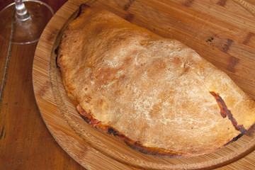 closed italian pizza calzone on a wooden plate