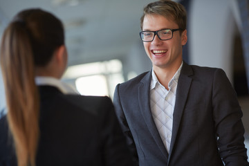 Young business woman and businessman talking in the hallway