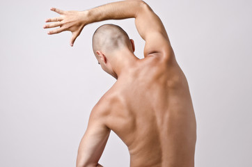 Topless man posing with his back. Fit stripper dancer training.