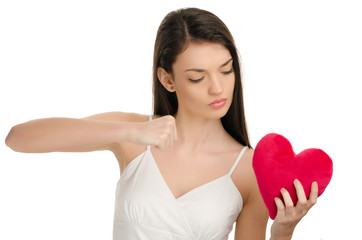 Upset girl punching a red heart unhappy love on Valentine Day. 