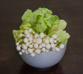 Golden needle mushroom with lettuce in white bowl.
