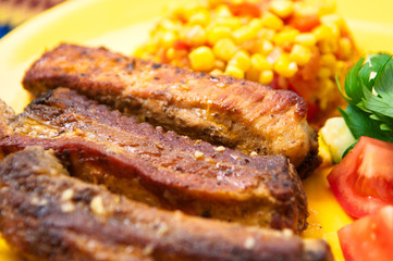 The pork chops with roasted corn on the yellow plate