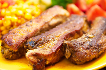 The pork chops with roasted corn on the yellow plate