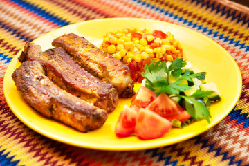 The pork chops with roasted corn on the yellow plate