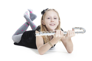 young blond girl holds flute lying down in studio © ahavelaar
