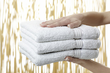 Frauenhände bieten einen Stapel Badetücher an