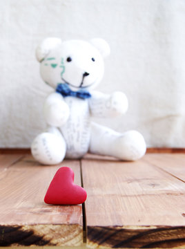 Heart and teddy bear on a wooden surface