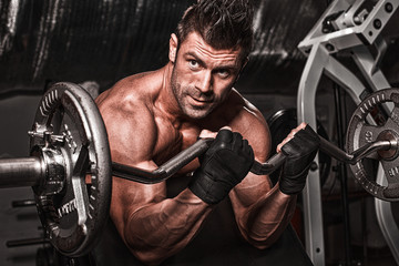 Fototapeta na wymiar Closeup of a muscular young man lifting weights on dark backgrou