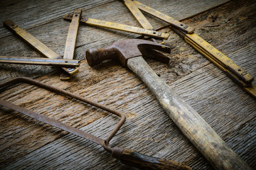 Hammer, Saw and Measuring Tape on Rustic Wood Background