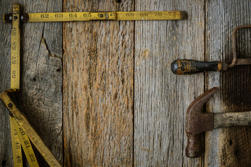 Measuring Tape Hammer and Saw on Rustic Old Wood Background