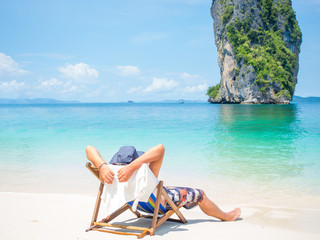 Man relaxing on the beach in Thailand - obrazy, fototapety, plakaty