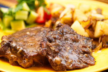 the roasted lamb with potatoes on the yellow plate