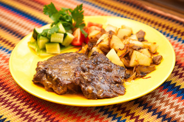 the roasted lamb with potatoes on the yellow plate