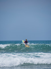 Beautiful young woman surfing in Kuta
