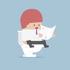 Businessman reading a newspaper in the toilet