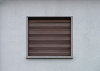 Fototapeta premium Graue Fassade mit geschlossenem braunen Rollladen