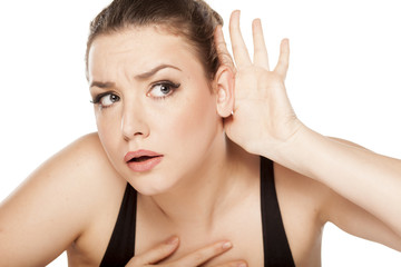 Fototapeta premium young woman holding a hand behind the ear and listens carefully
