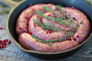 raw homemade sausages frying in a cast iron skillet