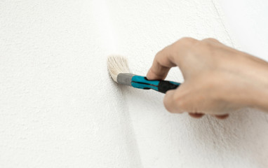 housepainter use paintbrush to white painting wall corner