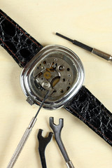 Schraubenzieher liegt auf geöffneter Armbanduhr